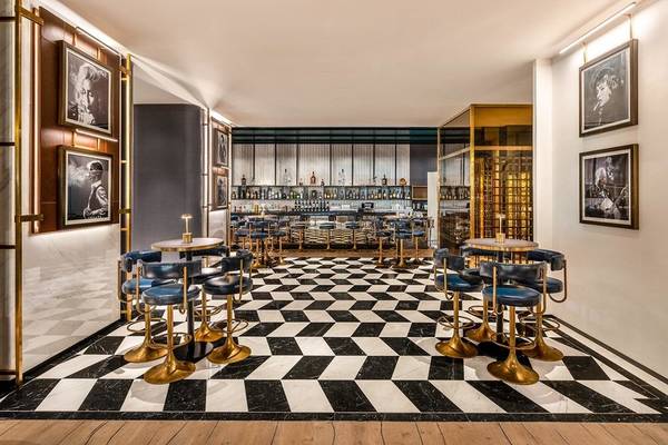 Innenbereich der Bar im Rixos Gulf Hotel Doha mit schwarzen und weißen Schachbrettboden und goldenen Stühlen.