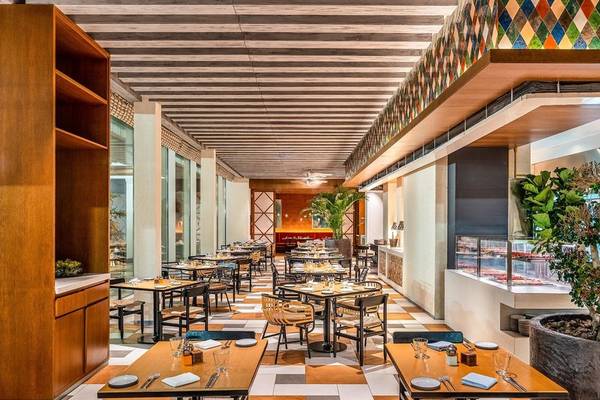 Innenansicht des Restaurants im Rixos Gulf Hotel Doha mit geometrischen Bodenfliesen und Holzmöbeln.