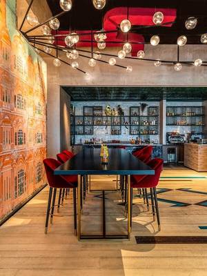 Innenbereich des Rixos Gulf Hotel Doha mit rotem Stuhlkreis und Bar im Hintergrund.