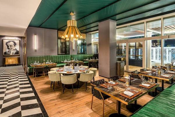 Innenbereich des Rixos Gulf Hotel Doha mit grüner Decke, grünen Sofas und Marmortischen.