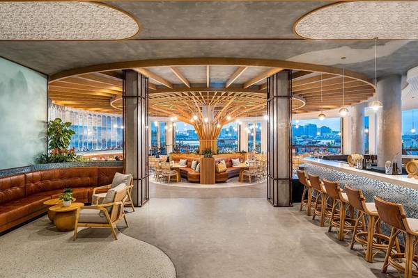Innenansicht der Lounge im Rixos Gulf Hotel Doha mit Holzmöbeln und Panoramafenstern.