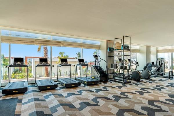 Fitnessstudio im Rixos Gulf Hotel Doha mit mehreren Laufbändern und Fitnessgeräten