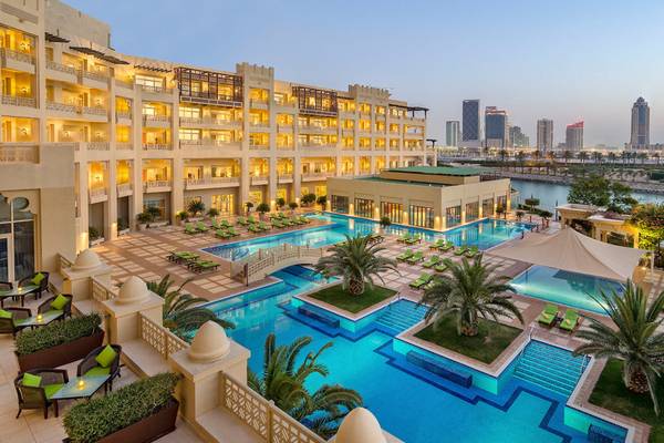 Außenansicht des Grand Hyatt Doha Hotel & Villas mit Swimmingpool, Loungebereich und Stadtpanorama.