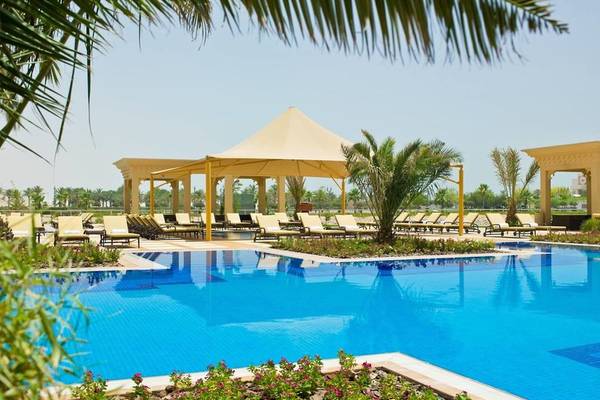 Außenpoolbereich des Grand Hyatt Doha Hotel mit Loungeliegen und Sonnenschirmen