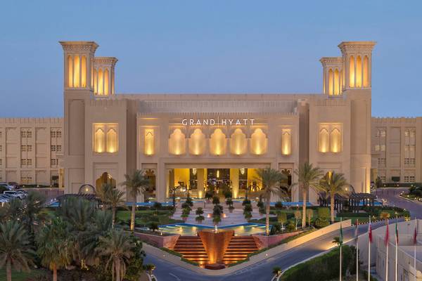 Nachtansicht des Grand Hyatt Doha Hotel & Villas mit beleuchteter Fassade und Brunnen im Vordergrund.