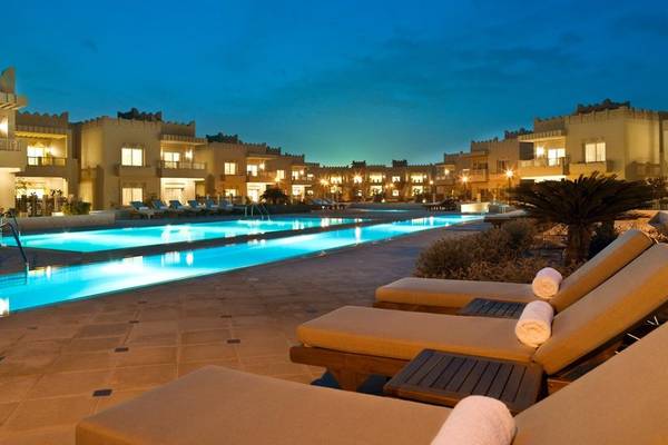 Nachtansicht des Swimmingpools und der Loungestühle im Grand Hyatt Doha Hotel & Villas.