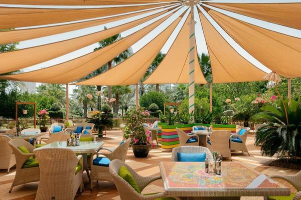 Terrasse des Grand Hyatt Doha Hotel & Villas mit bunten Tischen und Stühlen.