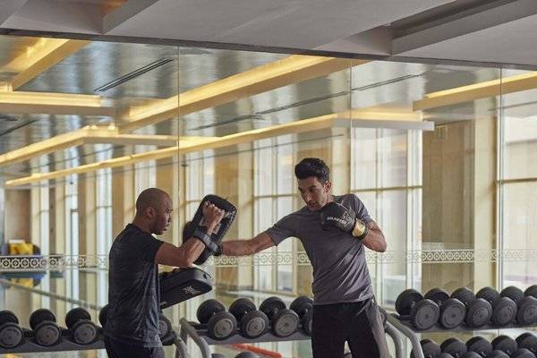Fitnesstraining im Grand Hyatt Doha Hotel & Villas mit zwei Männern, die Boxhandschuhe tragen.