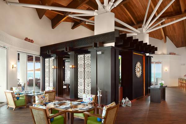 Innenbereich des Banana Island Resorts Doha von Anantara mit Holzboden, modernen Möbeln und Blick auf das Meer.