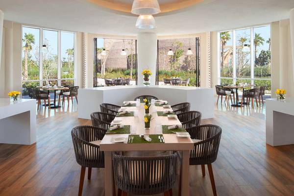 Innenansicht des Restaurants im Banana Island Resort Doha von Anantara mit großen Fenstern und hölzernem Boden.