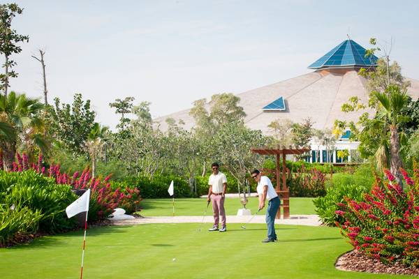 Zwei Männer spielen Golf auf dem Golfplatz des Banana Island Resorts Doha von Anantara.