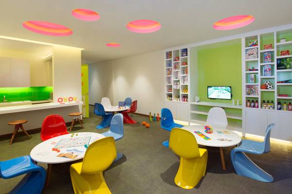 Spielzimmer im Banana Island Resort Doha by Anantara mit bunten Stühlen, Tischen und rosa Kreisen an der Decke.