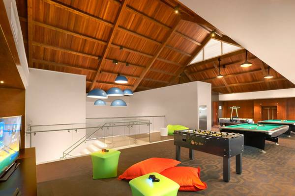 Spielzimmer im Banana Island Resort Doha von Anantara mit Billardtischen, Fernseher und bunten Möbeln.