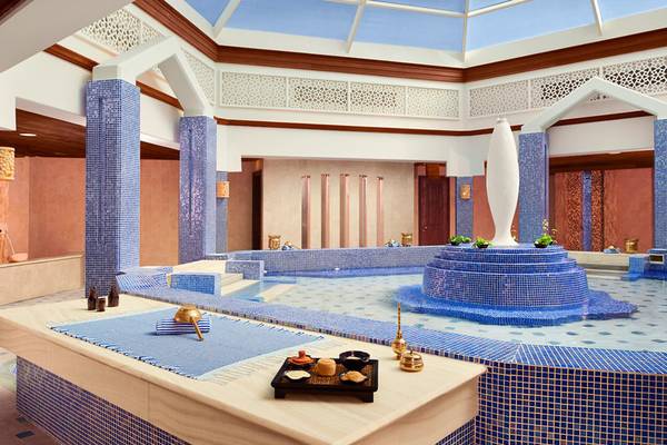 Innenansicht des Wellnessbereichs im Banana Island Resort Doha by Anantara mit blauen Mosaiken und einer zentralen Wasserfläche.