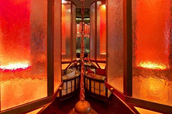 Inneneinrichtung des W Doha Hotel mit orange leuchtenden Trennwänden und Tischen.