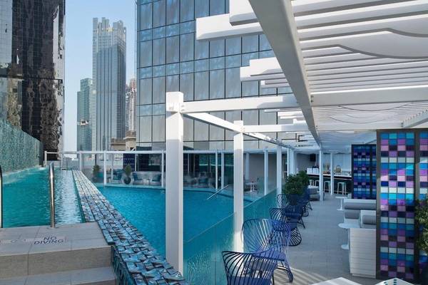 Außenbereich des W Doha Hotel mit Swimmingpool und Sitzgelegenheiten.