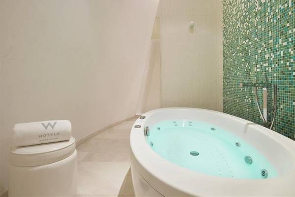 Badezimmer im W Doha Hotel & Residences mit Badewanne und türkisen Mosaikwand