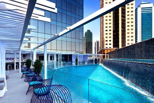 Pool im W Doha Hotel & Residences mit blauen Stühlen und Wasserfall.