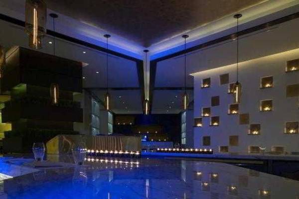 Innenansicht der Bar im W Doha Hotel & Residences mit blauen Beleuchtung und Marmortheke.