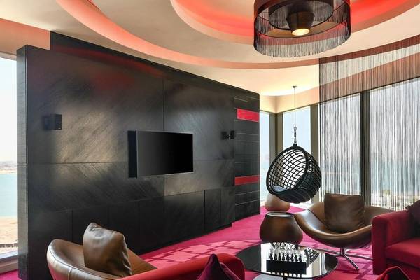 Innenbereich des W Doha Hotel & Residences mit schwarzen Wänden, roten Teppichen und modernen Möbeln.