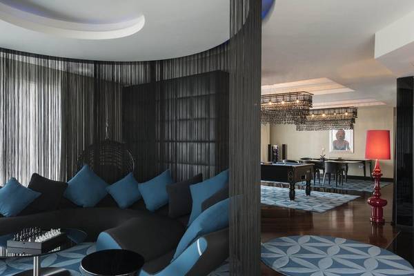 Lounge-Bereich des W Doha Hotel & Residences mit schwarzem und blauem Möbeldesign, Schachspieltisch und roter Stehlampe.