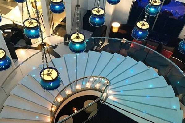 Innenansicht des Treppenhauses im W Doha Hotel & Residences mit blauen Pendelleuchten und blau beleuchteten Stufen.