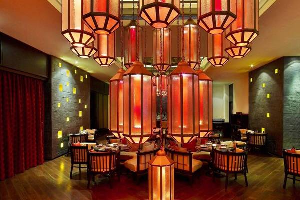 Inneneinrichtung des Restaurants im W Doha Hotel mit roten Lampen und hölzernem Boden.