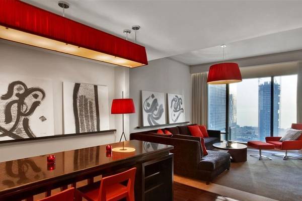 Wohnzimmer im W Doha Hotel & Residences mit roter Beleuchtung, Möbeln und Stadtblick.