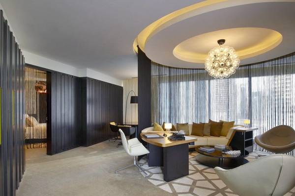 Inneneinrichtung des W Doha Hotel & Residences mit modernem Schreibtisch, Sofas und Deckenlampe.