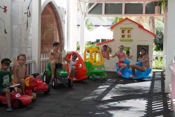 Kinder auf Spielzeugautos im Spielplatzbereich des Royal Taj Mahal Hotels