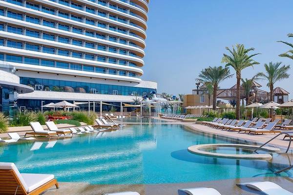 Ein großer Pool mit Loungeliegen vor dem Waldorf Astoria Doha Lusail Hotel.