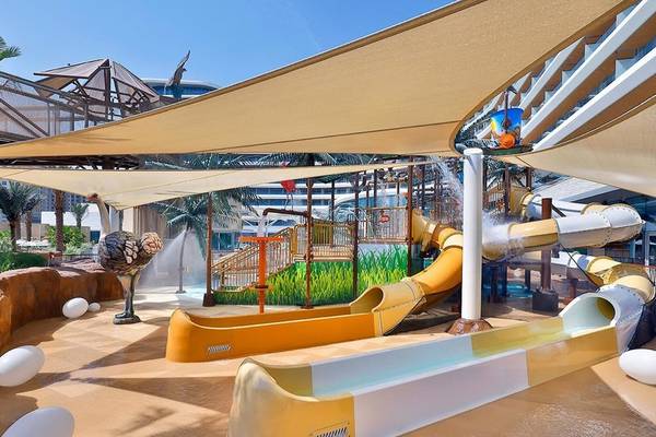 Wasserpark des Waldorf Astoria Doha Lusail mit gelben und weißen Rutschen.