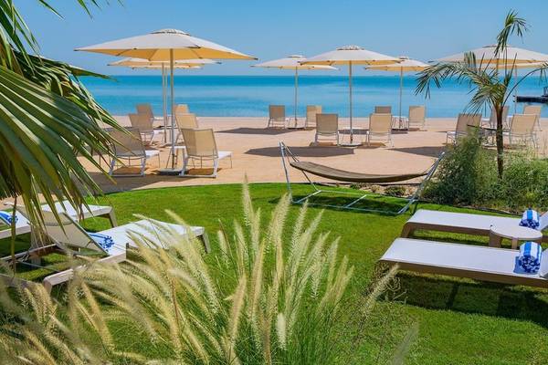 Strandbereich des Waldorf Astoria Doha Lusail Hotel mit Liegen und Sonnenschirmen