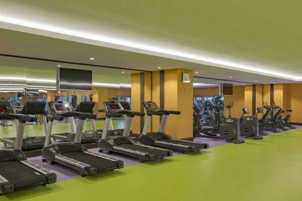 Fitnesscenter im Royal Taj Mahal Hotel mit mehreren Laufbändern und Spiegeln