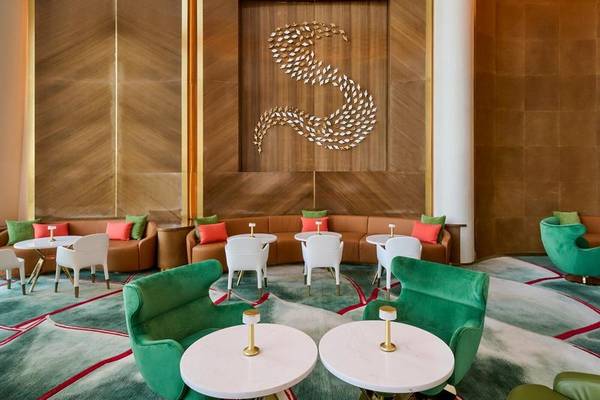Inneneinrichtung des Fairmont Doha Hotels mit grünen Stühlen, weißen Tischen und einer großen S an der Wand.