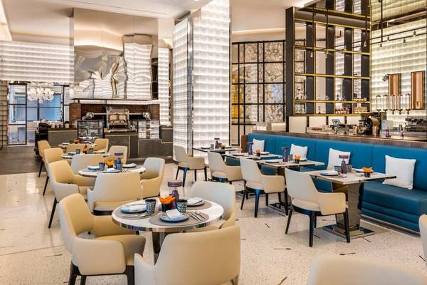Innenansicht des Restaurants im Fairmont Doha Hotel mit modernen Möbeln und blauen Sofas.