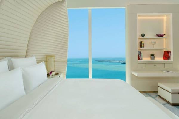 Fairmont Doha Hotelzimmer mit Blick auf das Meer und weiße Möbeln.