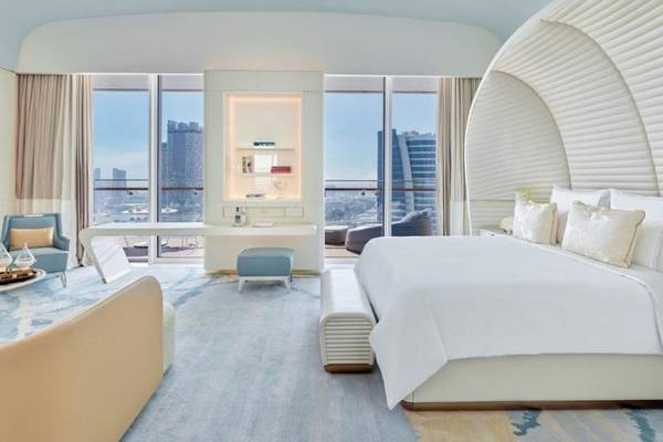 Ansicht eines Schlafzimmers im Fairmont Doha Hotel mit großer Bett, Fenstern und Blick auf die Stadt.