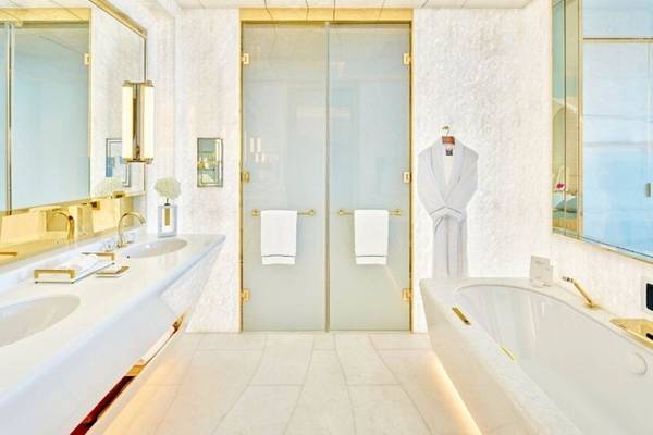 Ein elegantes Badezimmer im Fairmont Doha mit weißen Marmor und goldenen Akzenten.