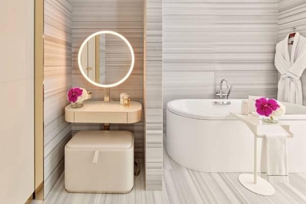 Badezimmer im Fairmont Doha Hotel mit weißem Badewanne, Spiegel und rosa Blumen.