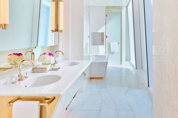 Luxuriöses Badezimmer im Fairmont Doha Hotel mit Marmorboden, zwei Waschbecken und einer Badewanne.