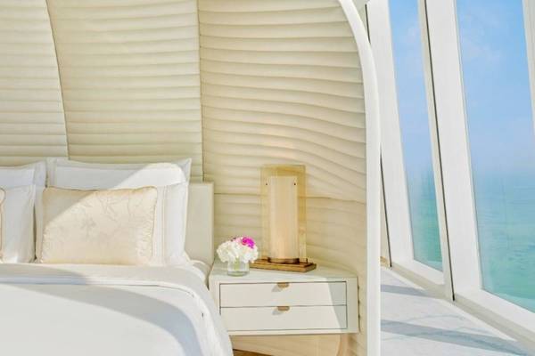 Schlafzimmer im Fairmont Doha mit Blick auf das Meer, weiße Bettwäsche und modernem Design.