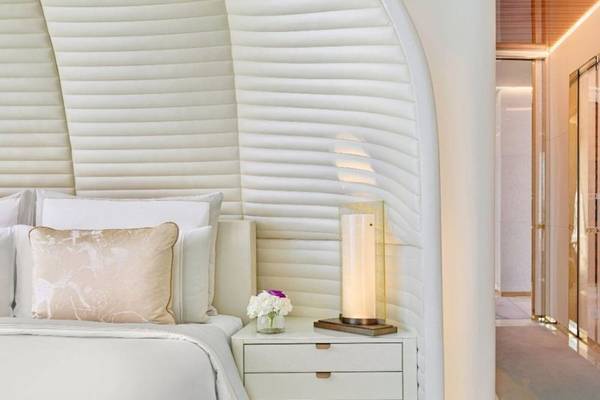 Schlafzimmer im Fairmont Doha Hotel mit weißen Möbeln, einem Bett, Kissen und einer Lampe auf dem Nachttisch.