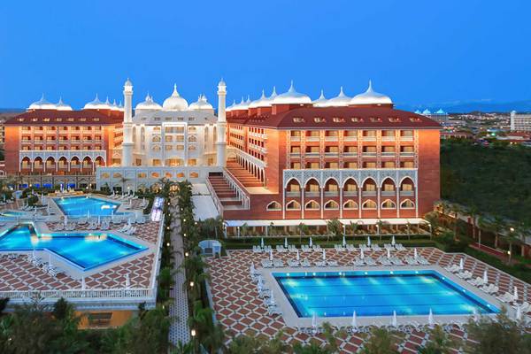 Luftaufnahme des Royal Taj Mahal Hotels mit zwei Swimmingpools und Loungebereichen bei Nacht