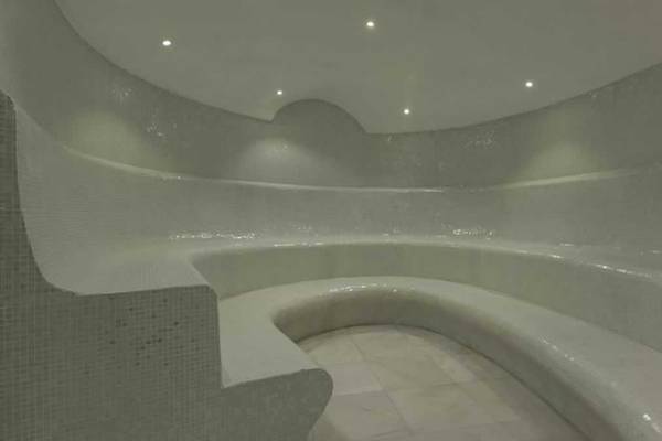 Innenansicht der Sauna im Royal Taj Mahal Hotel mit weißen Fliesen und gebogenen Bänken.