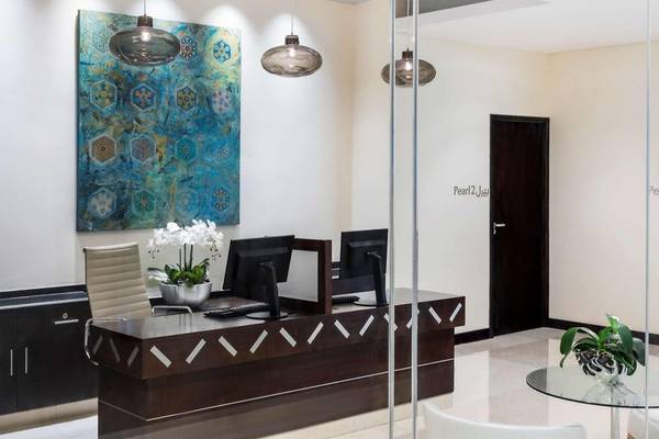 Empfangsbereich im Hyatt Regency Oryx Doha mit Schreibtisch, Monitoren, Kunstwerk und Pflanzen.