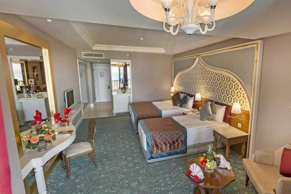Innenansicht einer Suite im Royal Taj Mahal Hotel mit zwei Betten, Tisch, Stühlen und einem Gemälde an der Wand.