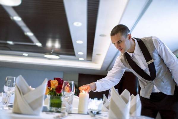 Kellner, der ein brennendes Kerze in einem eleganten Restaurant des Hyatt Regency Oryx Doha anzündet.