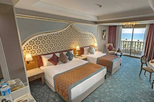 Doppelzimmer im Royal Taj Mahal Hotel mit Meerblick, zwei Betten, einem Balkon und einem großen Fenster.