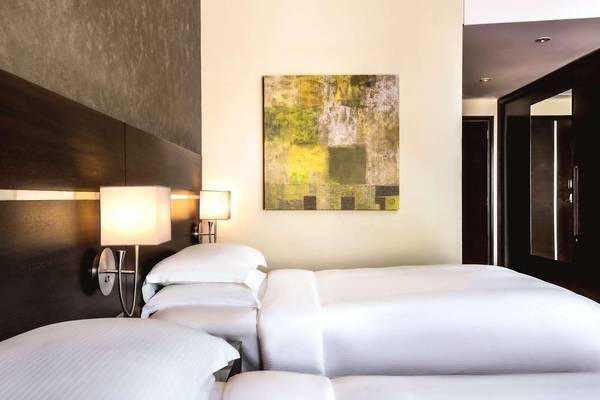 Schlafzimmer im Hyatt Regency Oryx Doha mit zwei Betten, Wandgemälde und Lampen.